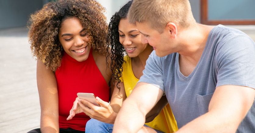 three friends using mobile phone